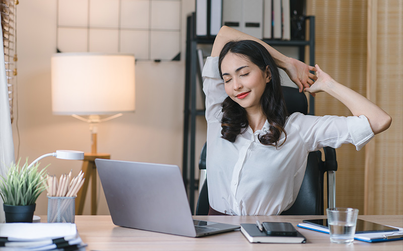 asian-woman-stretching-her-arms-behind-head-at-office-desk